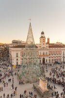 A large public square with a prominent glass pyramid structure, surrounded by historic buildings and a clock tower.
