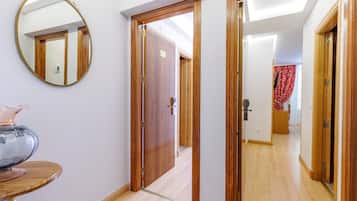 Un pasillo con puertas de madera, un espejo y una mesa con un florero.