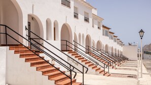 Ein Gebäude mit einer Treppe, die zu einer weißen Fassade mit Rundbogenfenstern und Balkonen führt.
