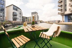 A boat with a table, a bottle of champagne, and a chair. - The Four Sisters Boatel (Edinburgh)