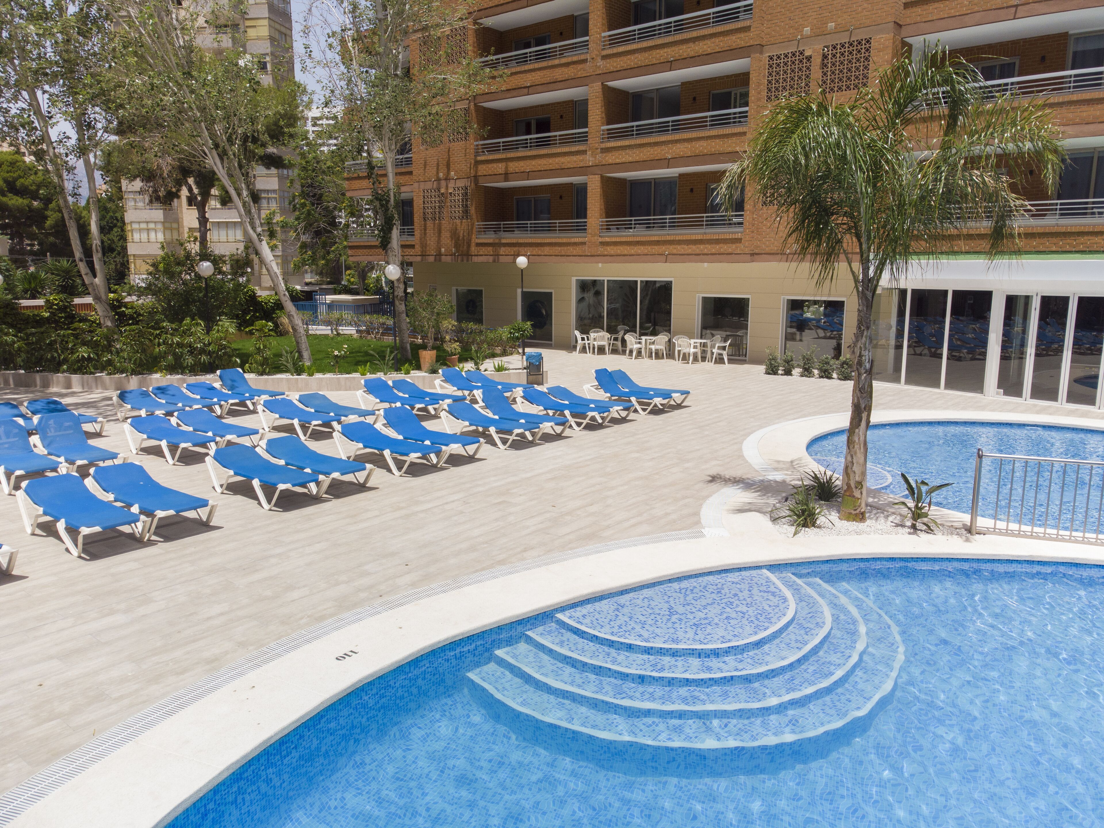A poolside area with blue lounge chairs and a swimming pool.