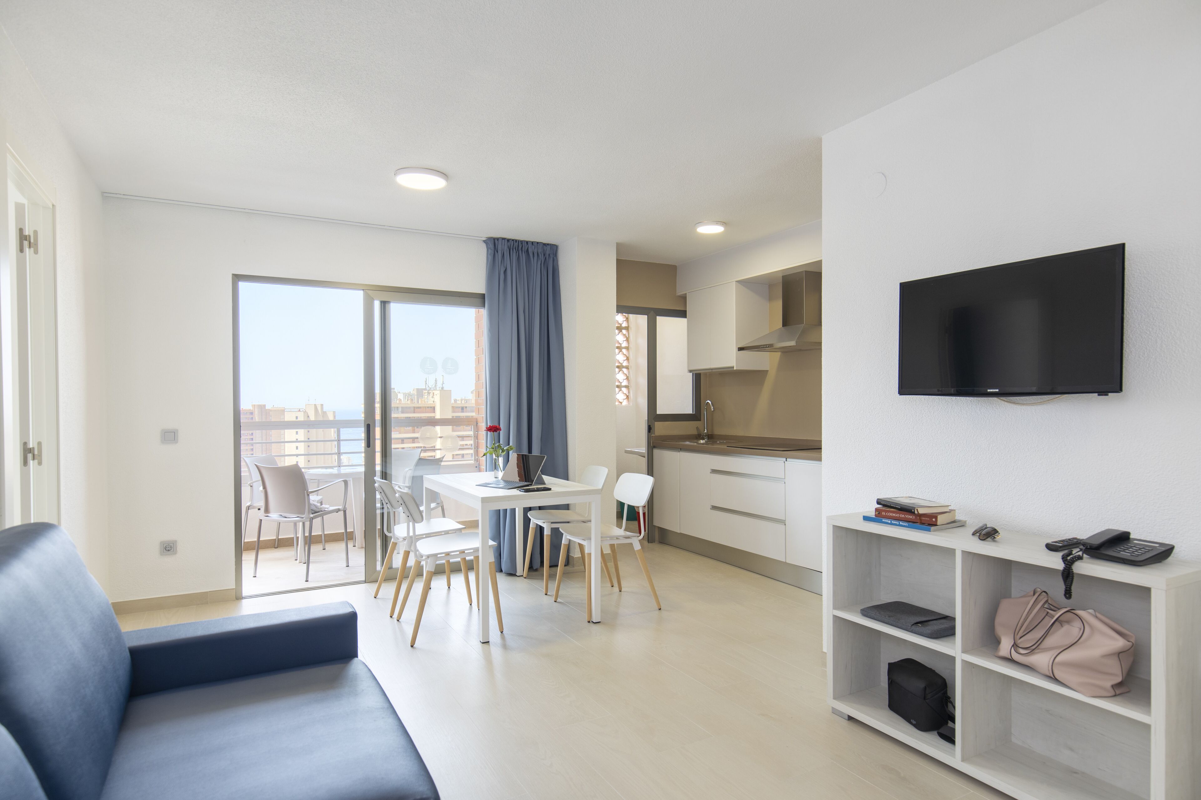 Un appartement moderne comprenant un espace de vie, un coin repas, une kitchenette et un balcon avec vue sur la ville.