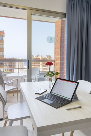 Een balkon met een laptop, een roos en een smartphone op een tafel.