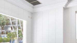 Ett modernt vardagsrum med en grå soffa, ett soffbord i glas och utsikt över omgivningen.