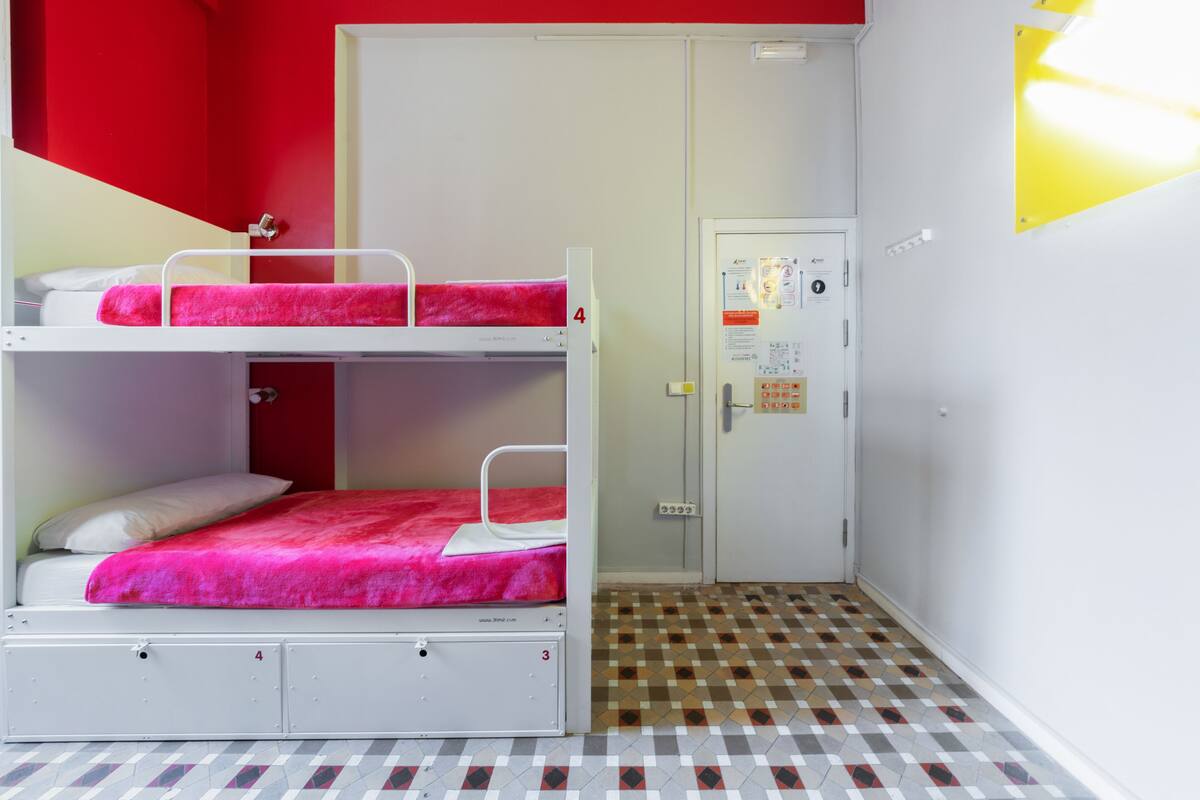Un dormitorio con literas, una puerta con un tablón de anuncios y un suelo estampado.