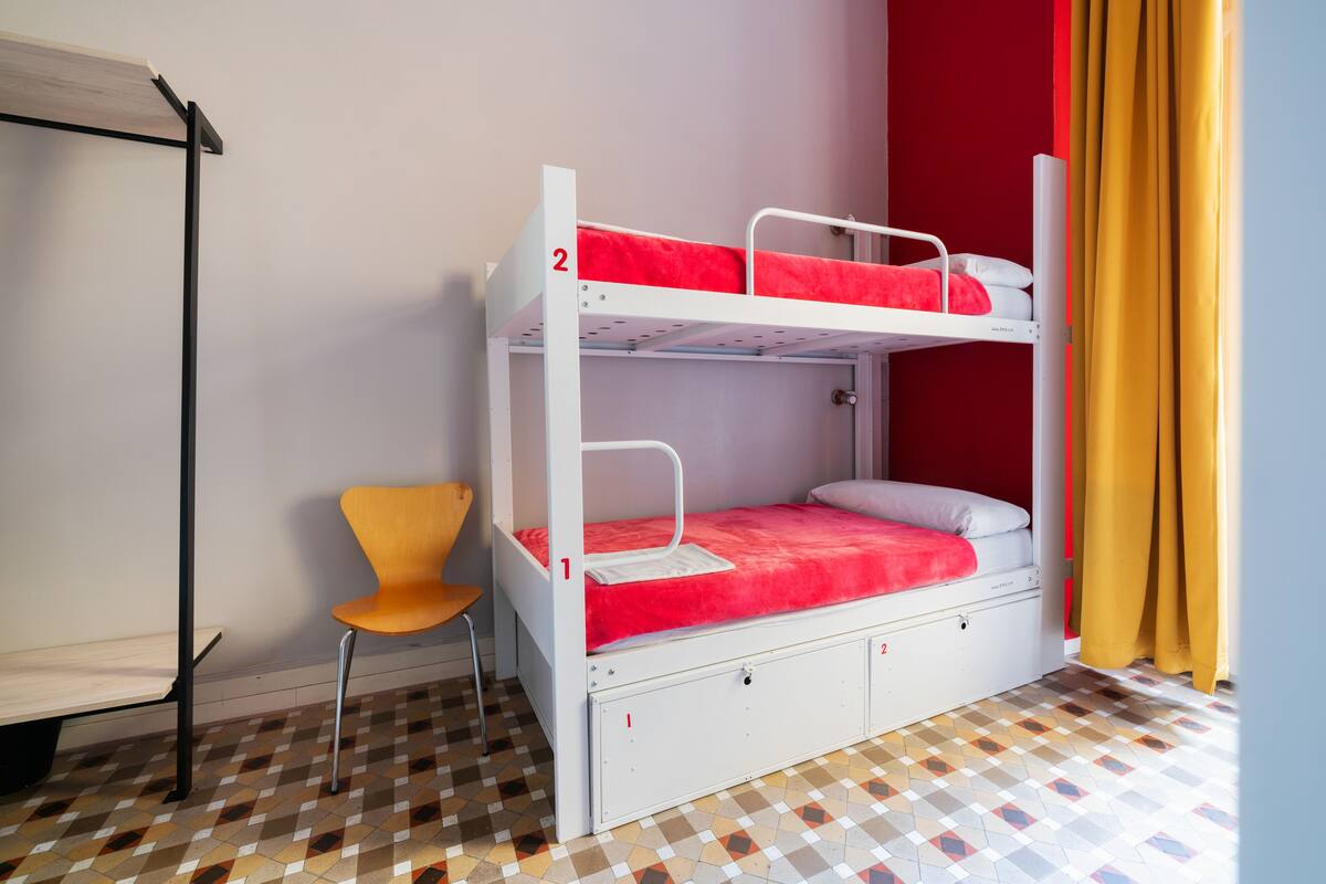 Una cama litera de dos plazas, una silla y un suelo con estampado.