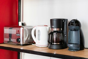 A kitchen counter with a toaster, a coffee maker, and a Keurig coffee pod machine. - Red Nest Hostel (Valencia)