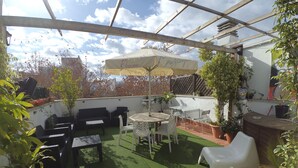 Un patio couvert avec une table et des chaises, un canapé et des plantes en pot.