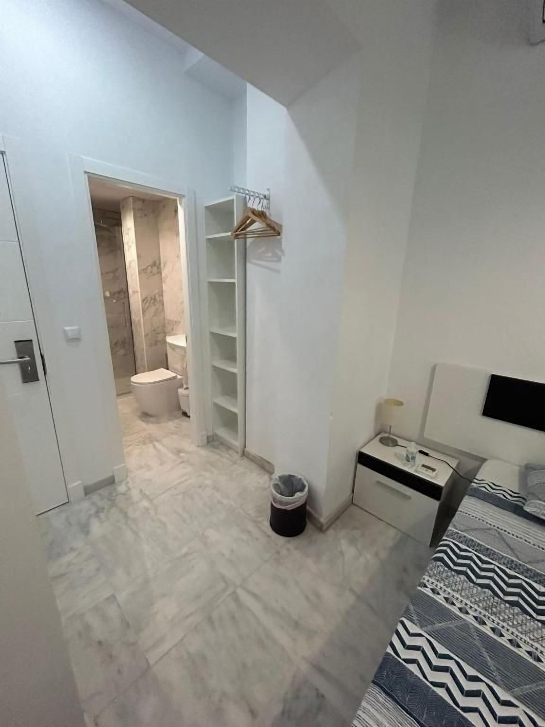 Une chambre à coucher comprenant un lit, une table de chevet, une armoire et une salle de bain avec des toilettes et un lavabo.
