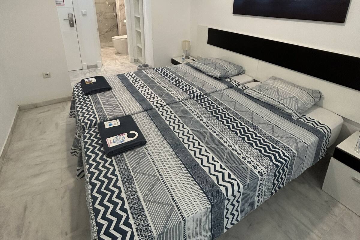 Quarto moderno com uma cama grande, uma mesa de cabeceira e ar-condicionado fixado na parede.