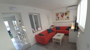 A living room with a red sofa, a white coffee table, and a patterned floor. - The Spot Central Hostel (Seville)