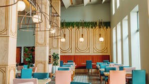 A restaurant interior with wooden paneling, hanging pendant lights, and a mix of blue and pink chairs. - Piazza Hotel Montecasino (Sandton)