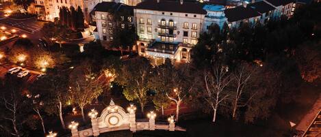 An aerial view of a historic cityscape with a prominent hotel labeled 'Piazza Hotel' featuring classical architecture, a central courtyard with a decorative fountain, and surrounding urban buildings.
