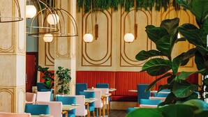 Ein Restaurant Innenraum mit Holzwandverkleidung, hängenden Pendelleuchten und Sitzgelegenheiten in Blau und Rosa.