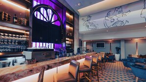 Eine Bar mit Theke, Stühlen und einer Wand mit Wandgemälde.