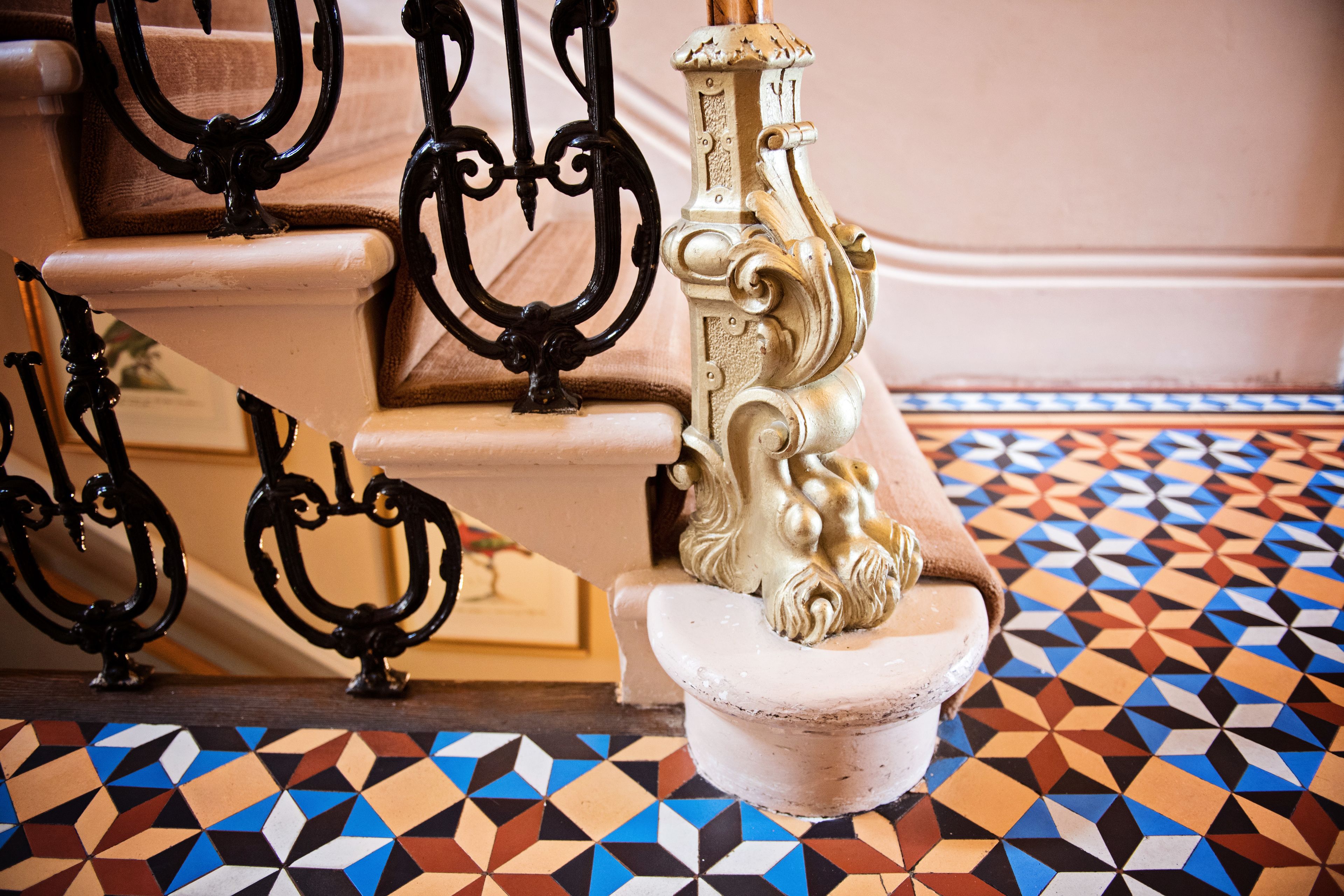 A staircase with ornate black metal railings and a patterned floor.