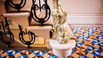 A staircase with ornate black metal railings and a patterned floor.
