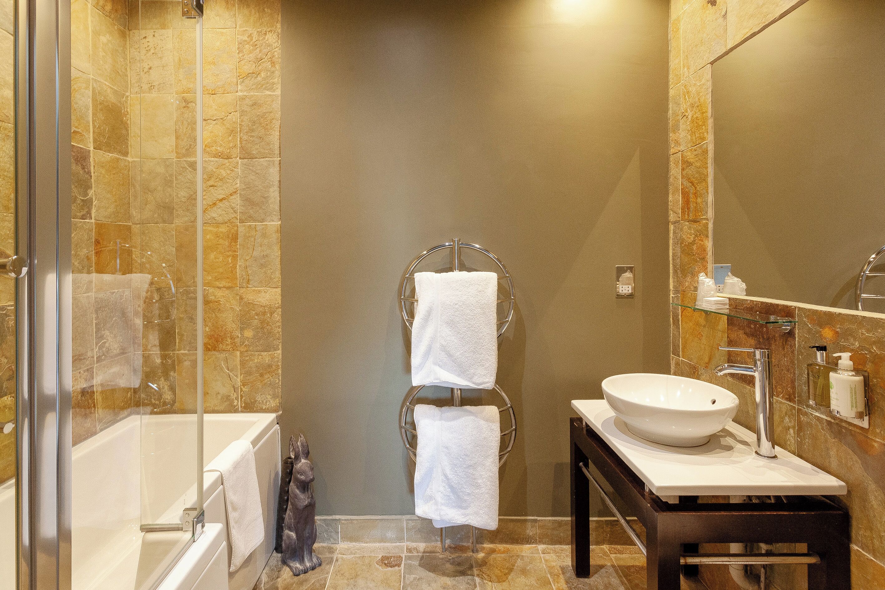 Une salle de bain équipée d’une baignoire, d’une douche à parois de verre, d’un lavabo avec un miroir et d’un porte-serviettes.