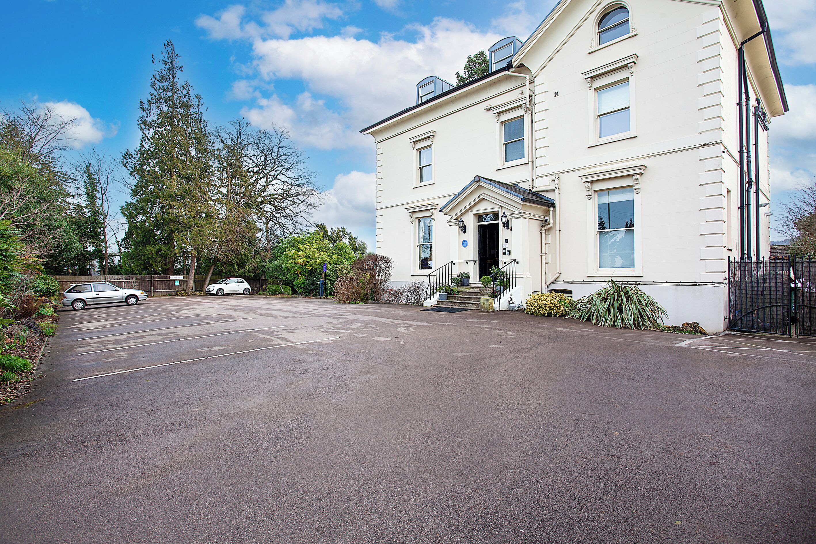A two-story building with a large driveway and parked cars.