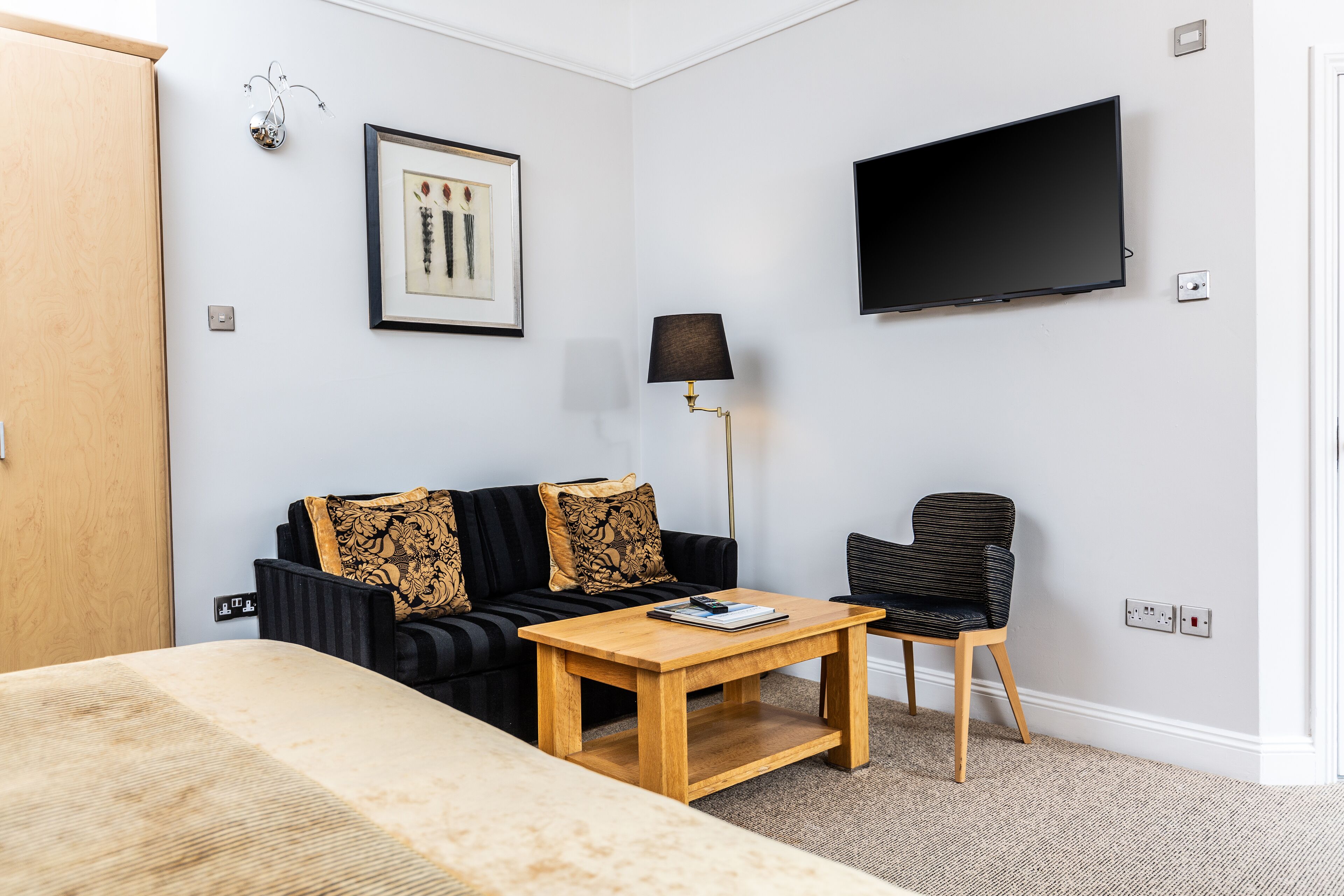 Une chambre d’hôtel moderne équipée d’un lit, d’un canapé, d’une table basse, d’une chaise, d’une télévision et d’une lampe.