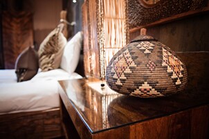 Una cama con un cojín estampado, una cesta tejida y un cabecero de madera.