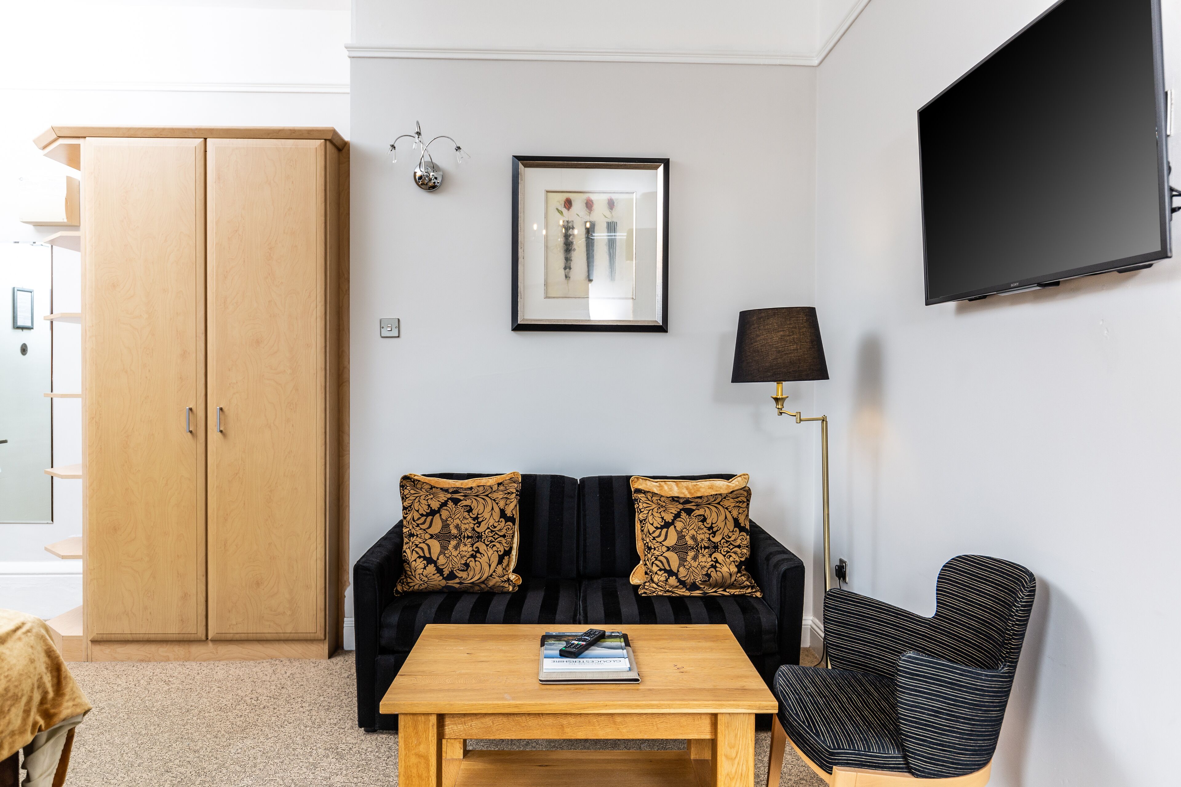 Un salon comprenant un canapé, une table basse, un téléviseur, une lampe et une armoire.