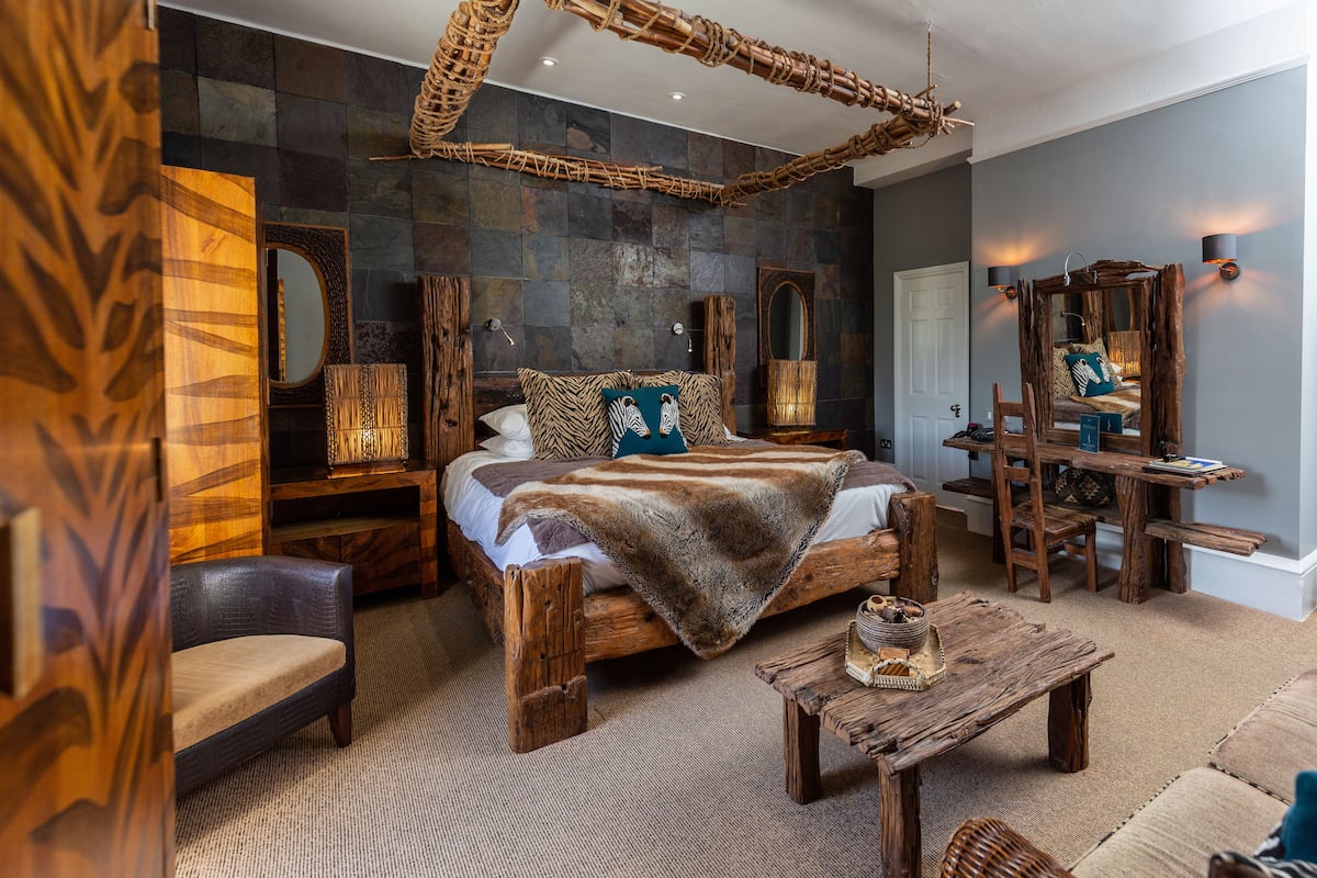 Un dormitorio con una cama grande, muebles de madera y una pared de piedra.