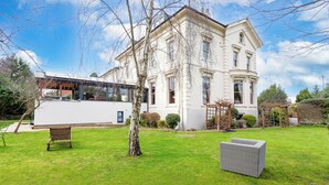 A large, historic building with a well-maintained lawn and outdoor seating area. - Beaumont House (Cheltenham)