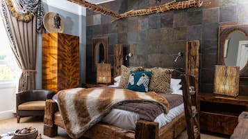 Une chambre à coucher au style rustique, avec un grand lit, une tête de lit en bois et un mur en pierre.