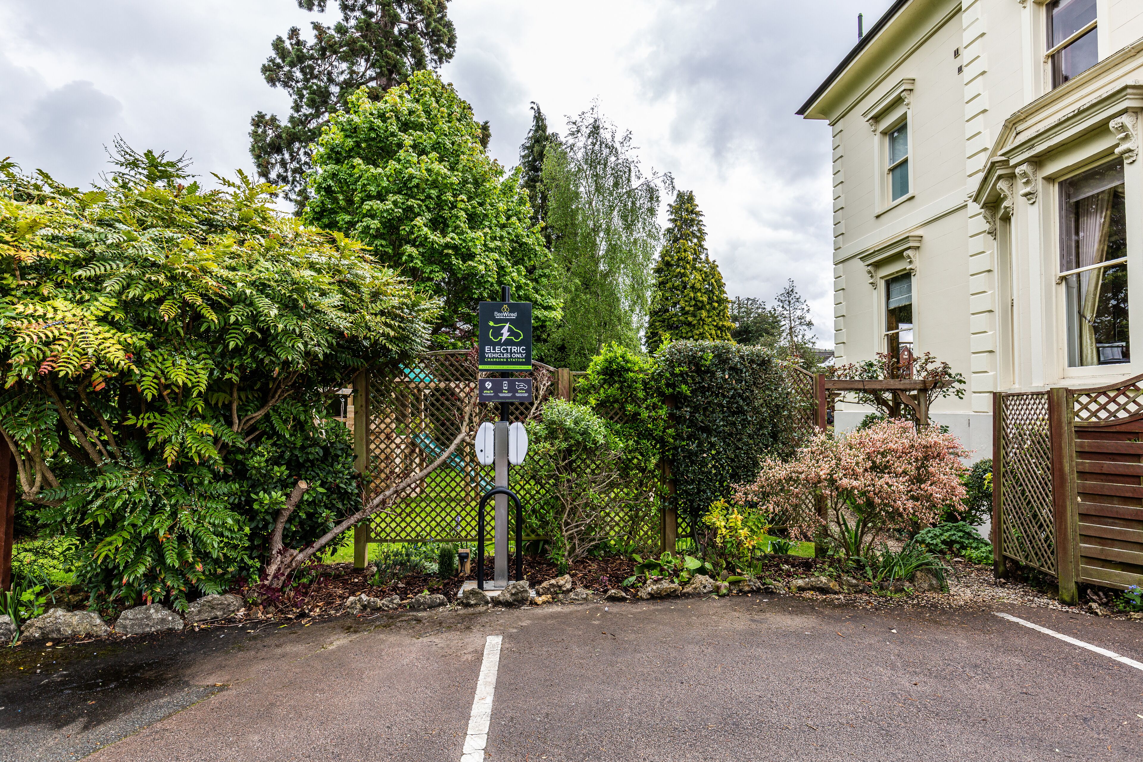 A gated entrance with a sign indicating electric vehicle charging facilities.