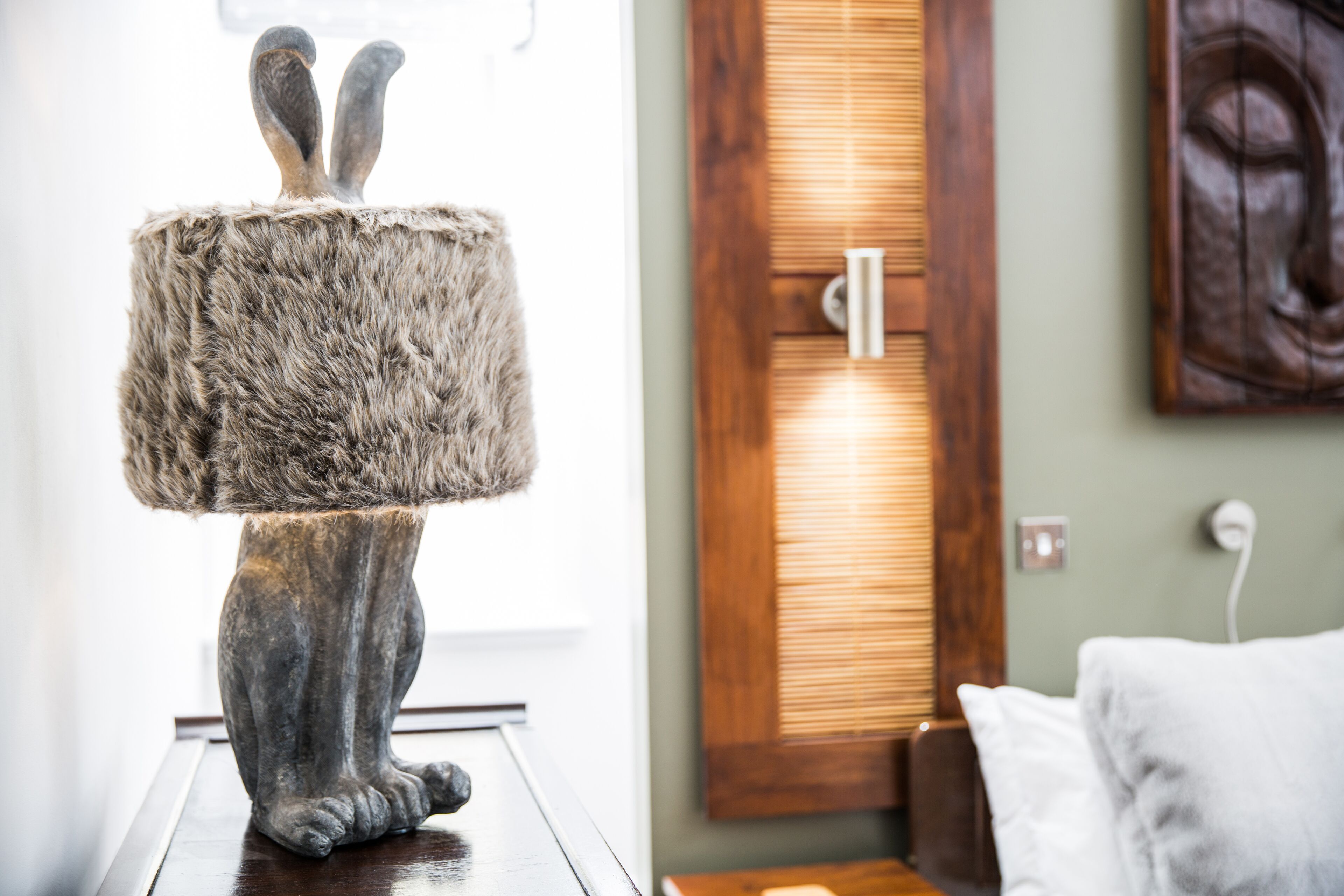 A statue of a rabbit with a large fur-covered base on a wooden table.