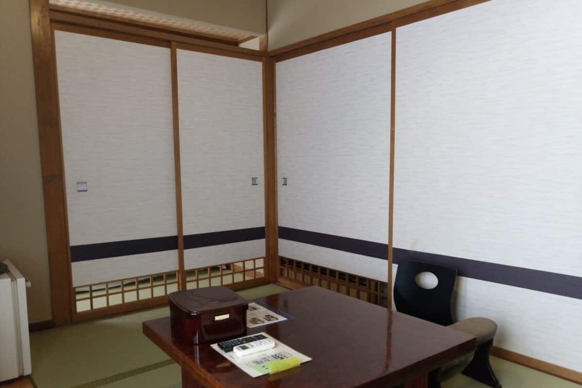 A traditional Japanese room with tatami flooring, a low wooden table, a chair, and shoji screens.