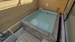 Une petite piscine intérieure avec des murs en bambou et une bordure en pierre.