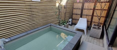 A small outdoor swimming pool with a bamboo fence, a white plastic chair, and a sign that reads "DANGER".