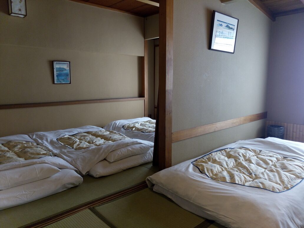 Una habitación con dos camas, un cuadro en la pared y techo de madera.