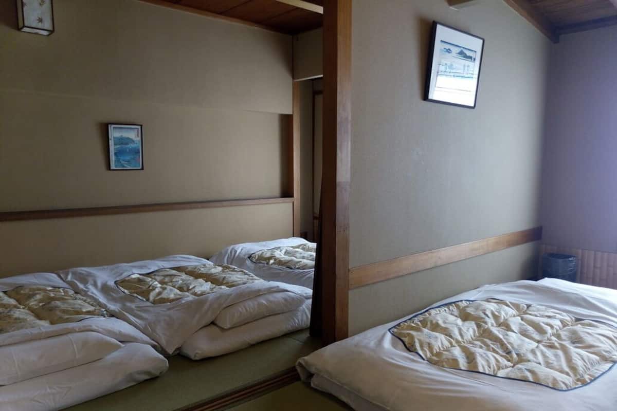 A room with two beds, a framed picture on the wall, and a wooden ceiling.
