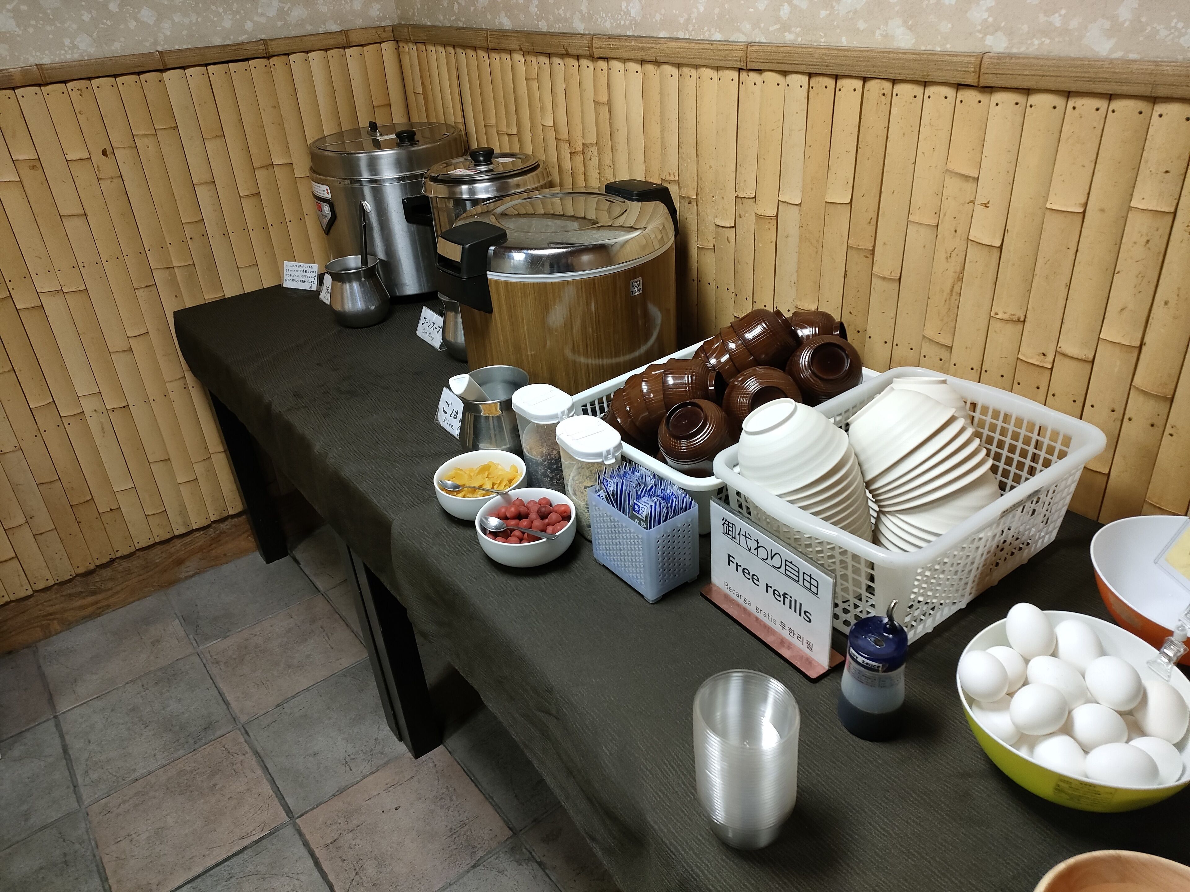 Une table de buffet garnie de divers aliments et d’ustensiles, notamment des bols, des assiettes et des récipients.