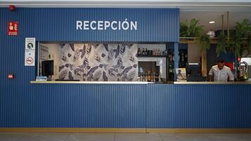 Zona de recepción con pared azul, estampado floral y mostrador con diversos objetos.