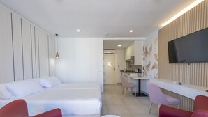 Una habitación de hotel moderna con una cama, un escritorio, un televisor y sillas rojas y rosas.