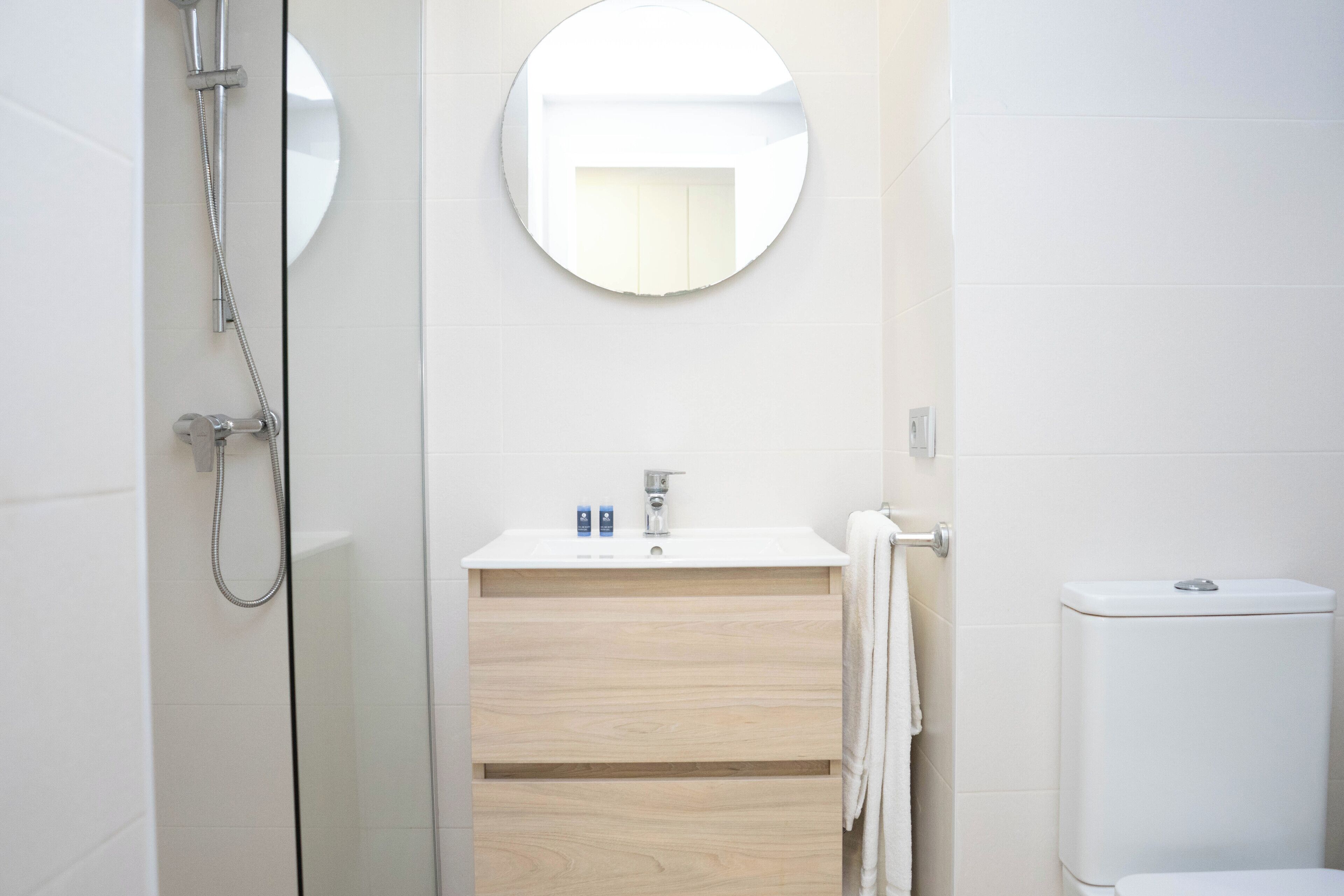 Un baño moderno con ducha, lavamanos con espejo y retrete.