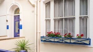 A building facade with a blue door labeled "THE LOFT," a window with red flowers, and a blue railing. - Dolphin Inn (London)