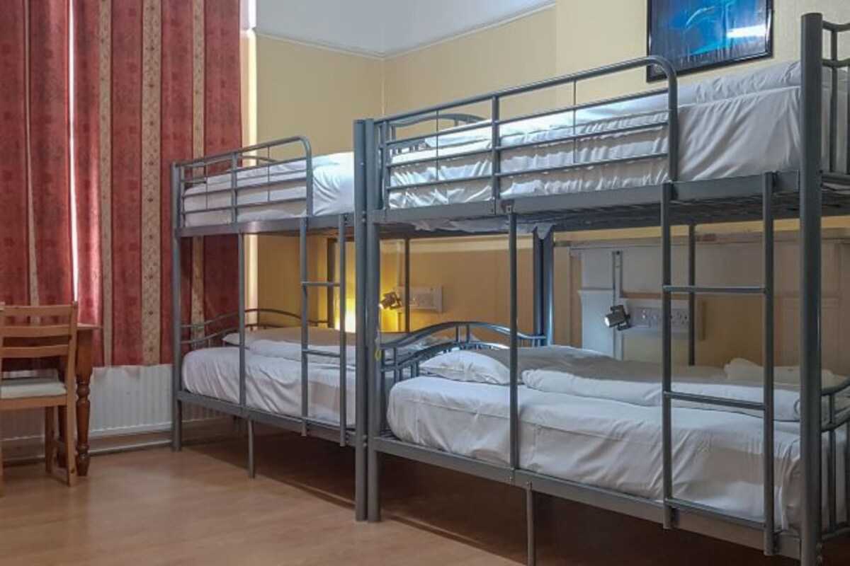 A bunk bed room with a wooden chair and a radiator.
