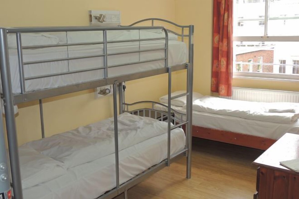 Habitación con literas, ventana y radiador.