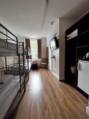 A room with bunk beds, a small desk, a chair, a television, and a wardrobe. - Dolphin Inn (London)