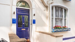 A blue door with the number 44 and the name "The Lodge" above it, flanked by two signs reading "Dolphin Inn". - Dolphin Inn (London)