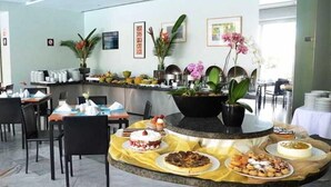 Un hall d’hôtel avec un buffet, des chaises et des plantes en pot.