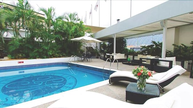 Un espace piscine avec des chaises longues et une petite table agrémentée d’un vase de fleurs.