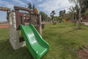 Ein Spielplatz mit einer grünen Rutsche und Klettergerüsten.