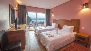 Habitación de hotel con dos camas, un escritorio con televisor y vista al exterior.