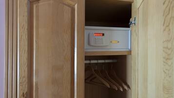 Un armario de madera con cerradura digital y perchas en su interior.